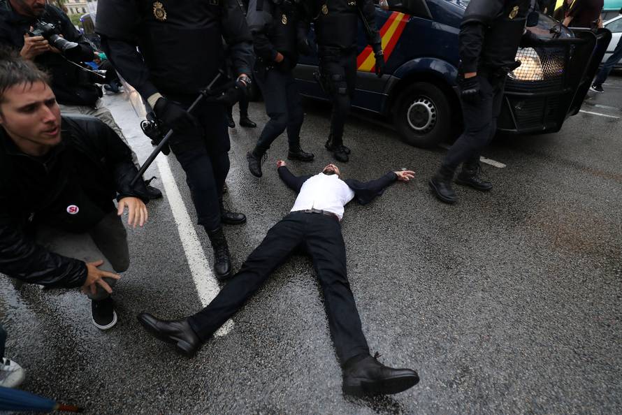 Riot police remove demonstrators outside a polling station for the banned independence referendum in Barcelona