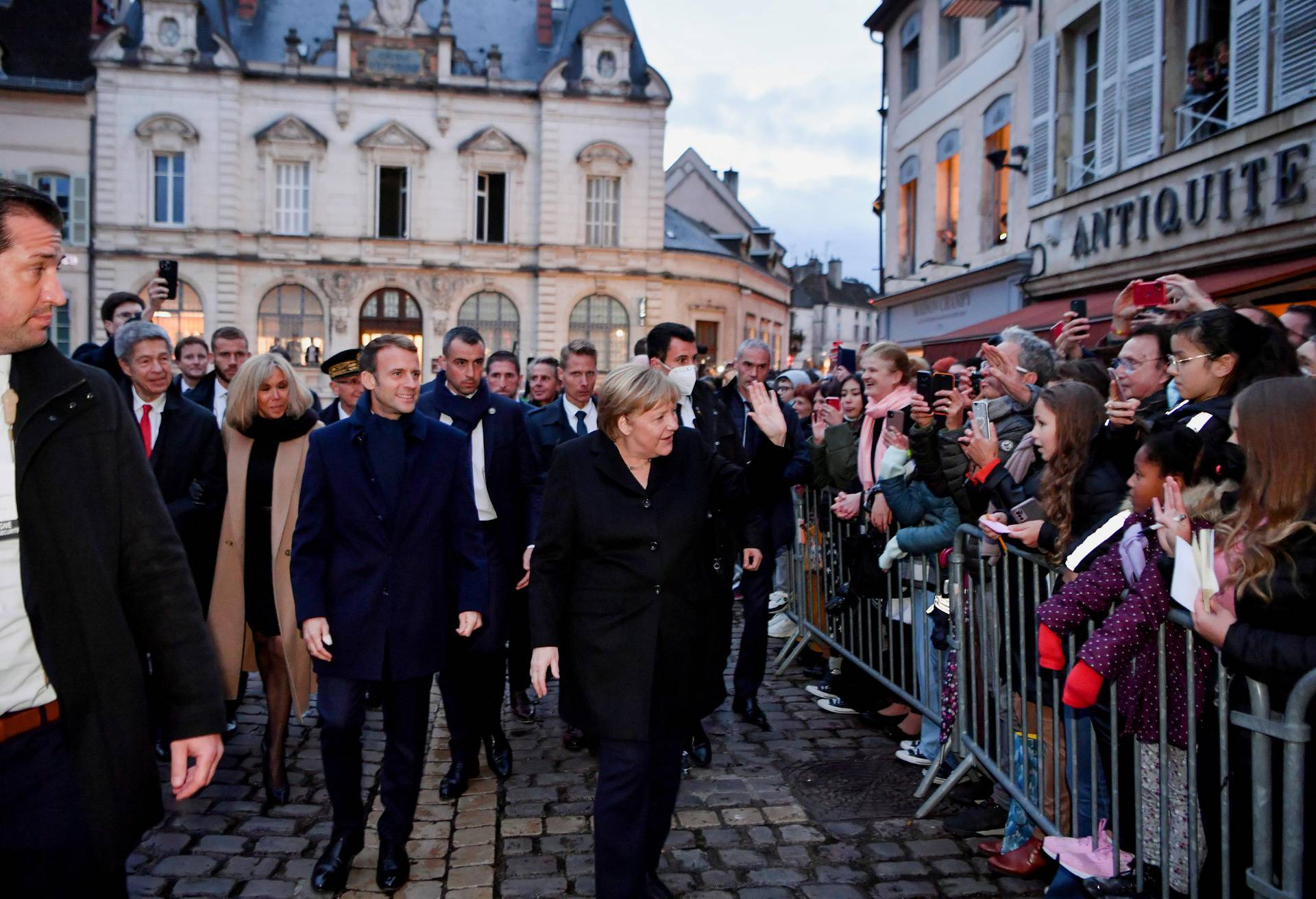 France's President Emmanuel Macron, flanked by his wife Brigitt Macron, is greeted by members of the public with outgoing German Chancellor Angela Merkel upon their arrival prior to talks, in Beaune
