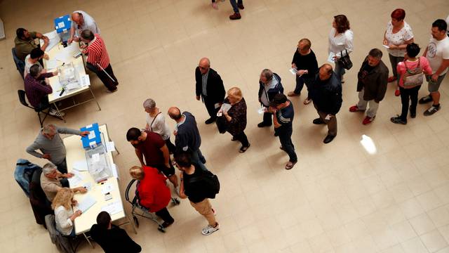 People queue to cast their votes for the European Parliament and local elections at a polling station in Barcelona