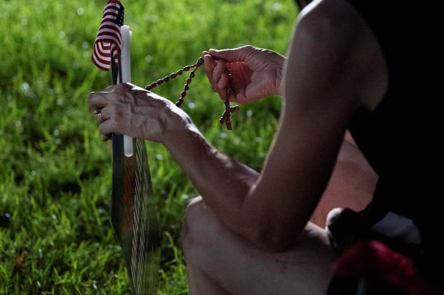 A woman holds rosary beads as Catholics from across the Phoenix area gather to pray for Charlie Kirk, who was shot and killed in Utah, at Desert Horizon Park in Scottsdale