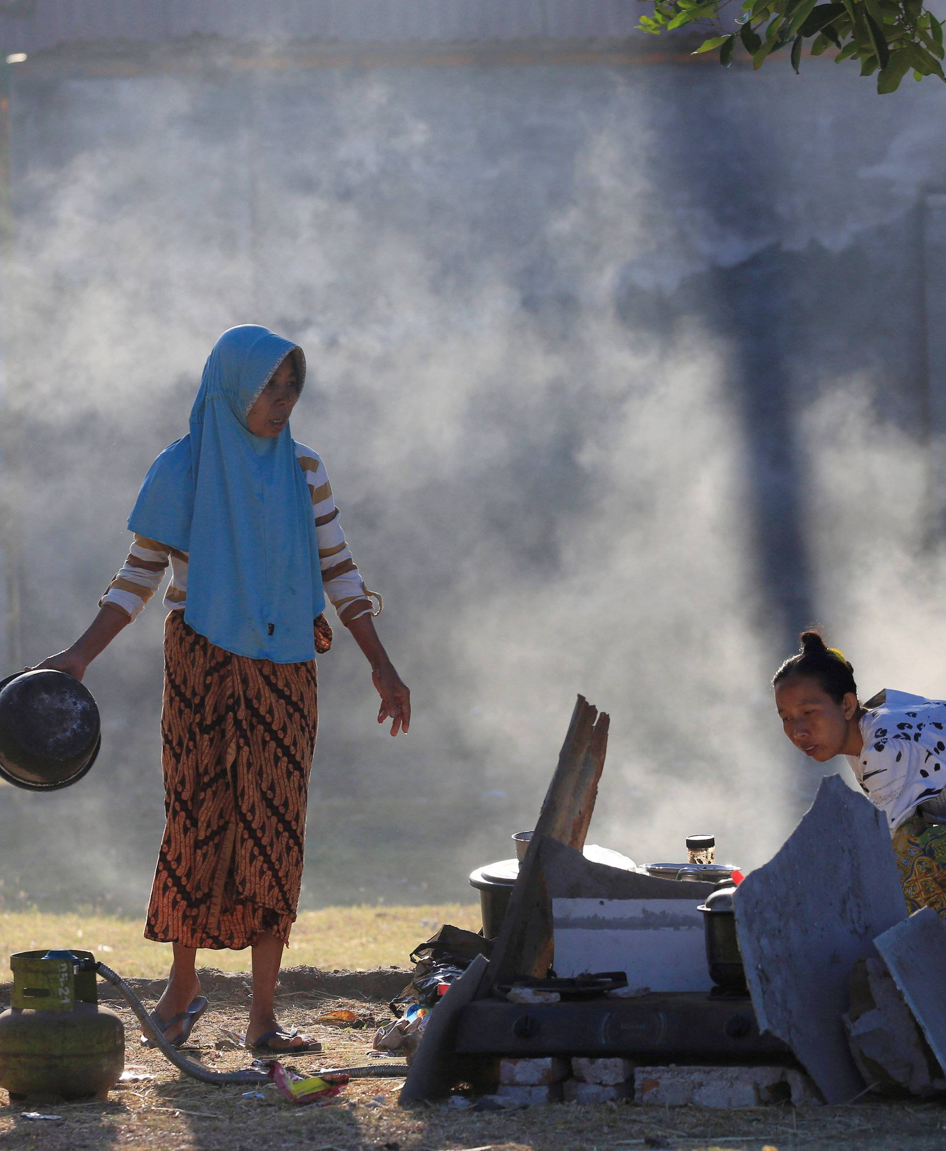 Villagers cook at their temporary shelter after an earthquake hit on Sunday in Pemenang
