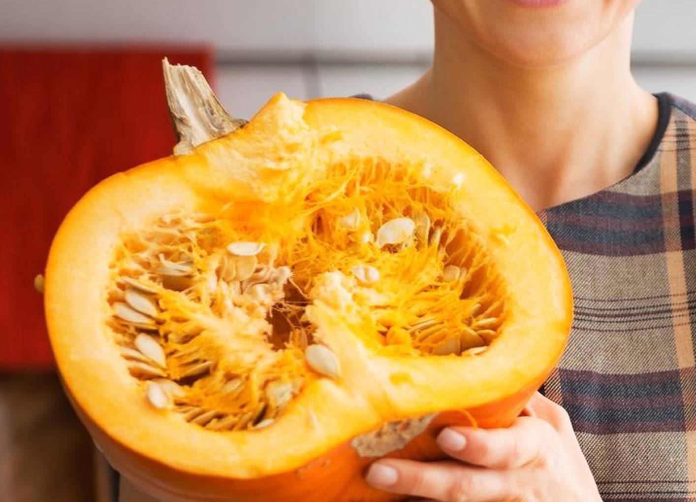 Portrait of happy young housewife showing half of pumpkin