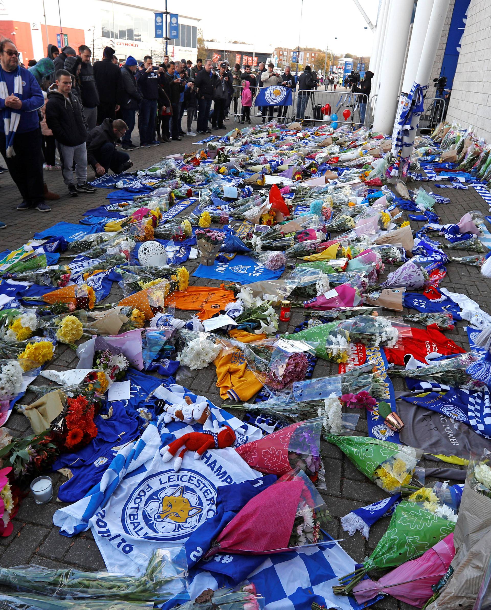 Leicester City football fans pay their respects outside the football stadium, after the helicopter of the club owner Thai businessman Vichai Srivaddhanaprabha crashed when leaving the ground on Saturday evening after the match, in Leicester
