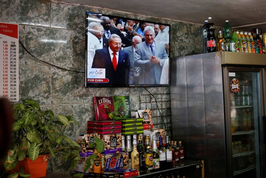 Cuba's President Raul Castro and  First Vice-President Miguel Diaz-Canel are seen on a TV screen inside a restaurant as they arrive for a session of the National Assembly in Havana