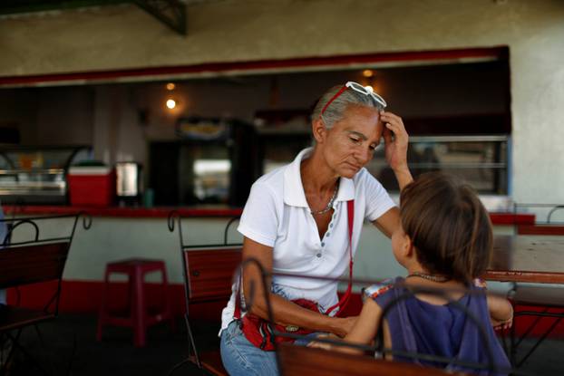 Zulay Pulgar rests in a coffee shop with her son Emmanuel after standing in line to buy cement in a hardware store in Punto Fijo