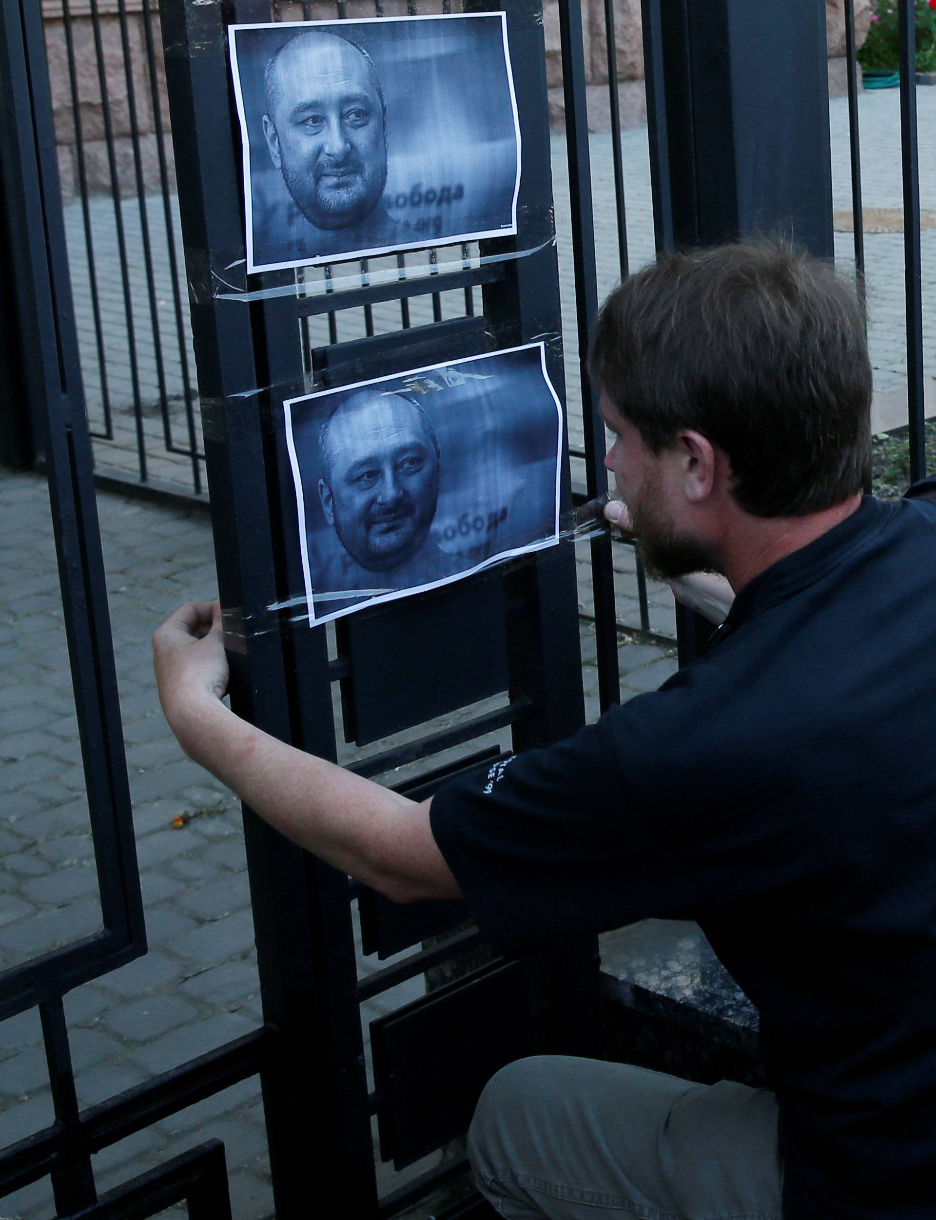 A man hangs a picture of Russian dissident journalist Babchenko, who was shot dead in the Ukrainian capital on May 29, on a fence of the Russian embassy in Kiev