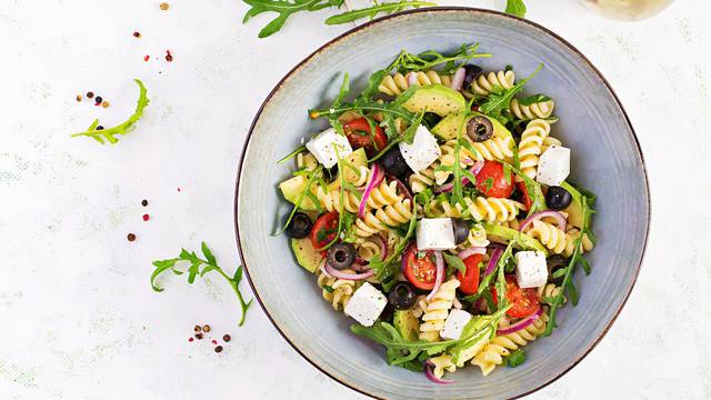 Pasta salad with tomato, avocado, black olives, red onions and c