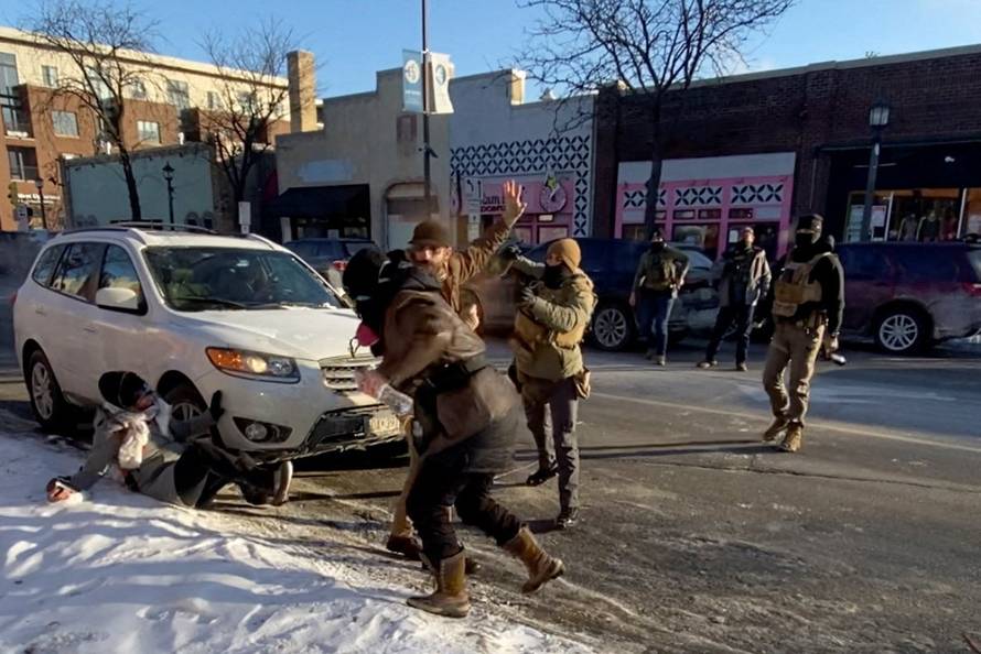 Law enforcement officers kneel next to the body of a man who was shot when federal agents were trying to detain him in Minneapolis