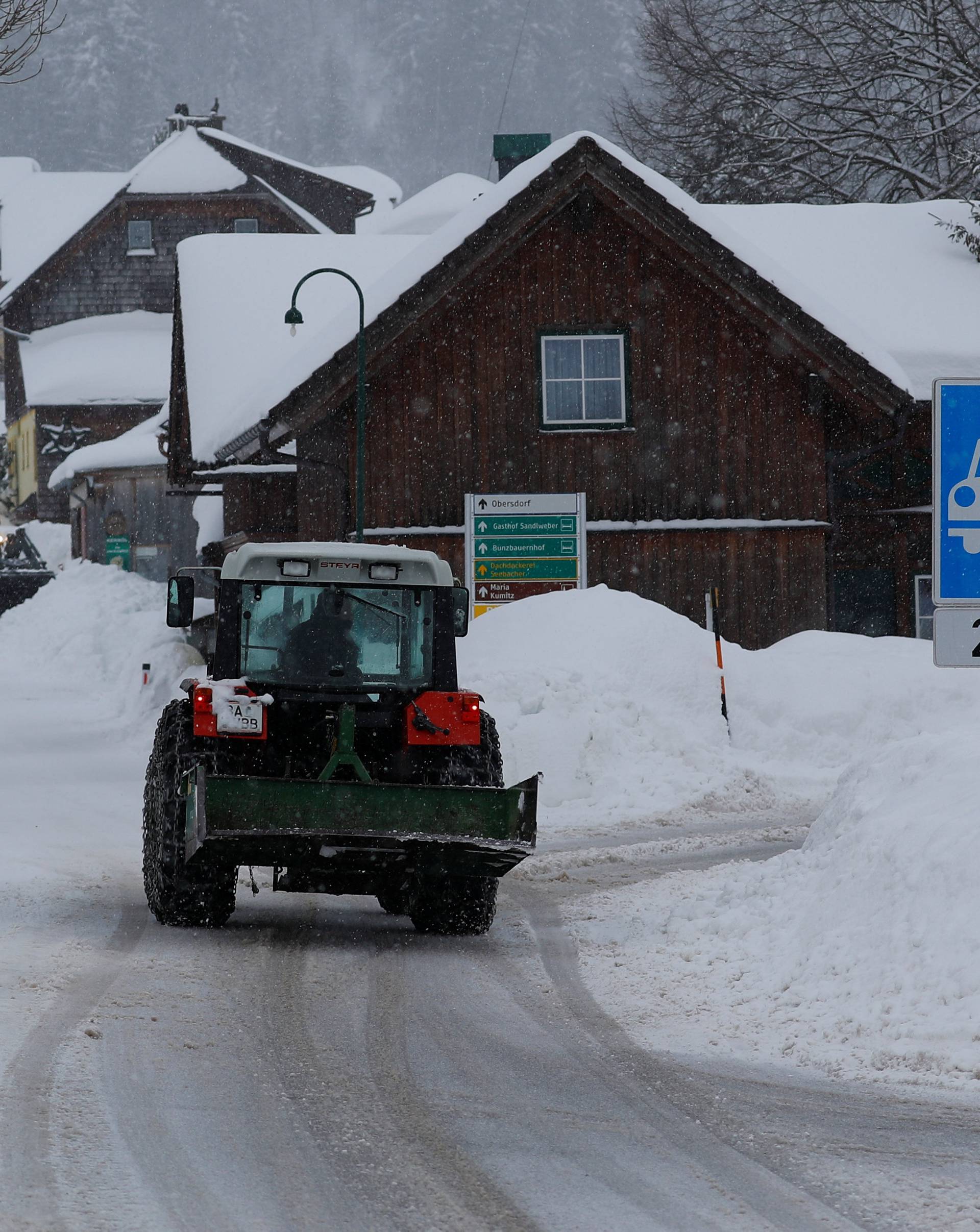 A tractor shovels snow on an icy road after heavy snowfall in Knoppen