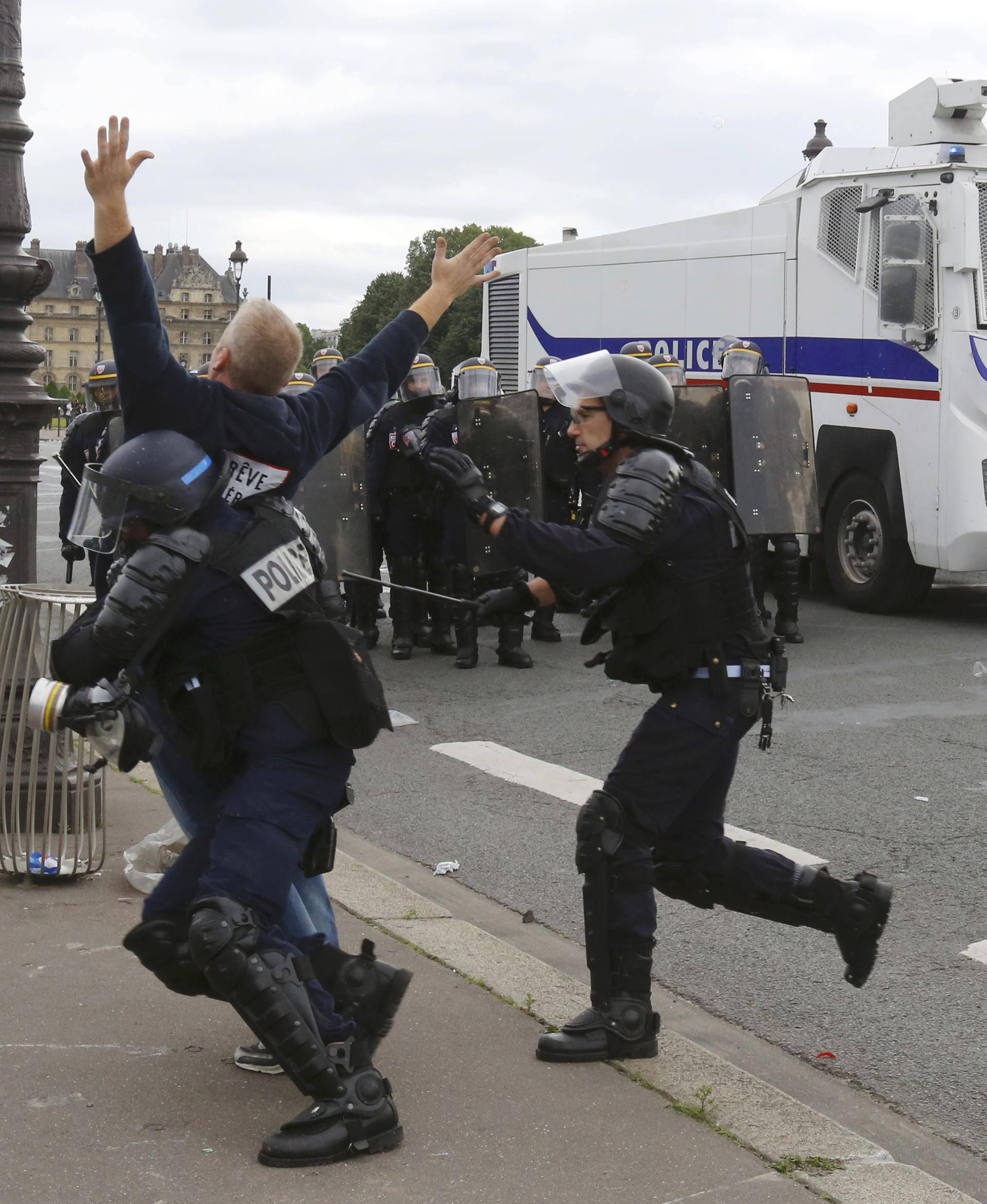 French CRS riot police apprehend a demonstrator during clashesat the Invalides square during a demonstration in Paris