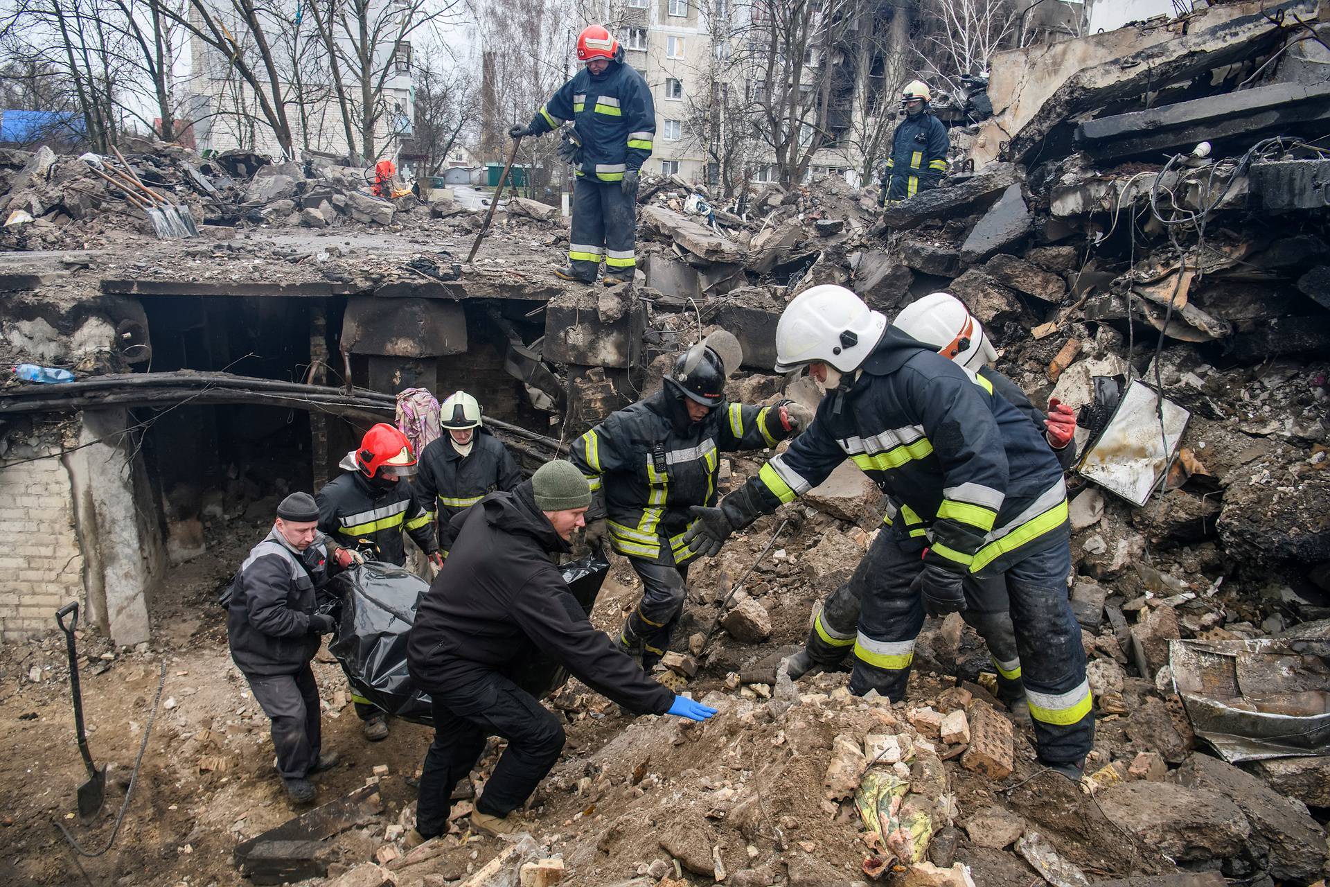 Rescuers carry a body of a person found under debris of a residential building destroyed during Russia’s invasion in the town of Borodianka