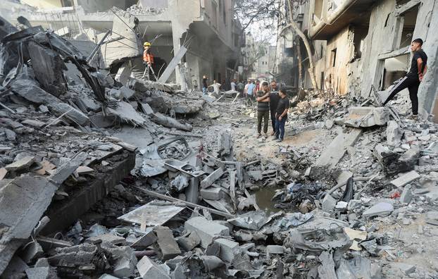 Palestinians inspect a house hit in an Israeli strike, in Nuseirat refugee camp