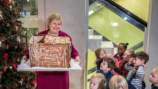 Norway's Prime Minister Erna Solberg holds a ginger bread house given by children from a local kindergarten visiting her office in Oslo