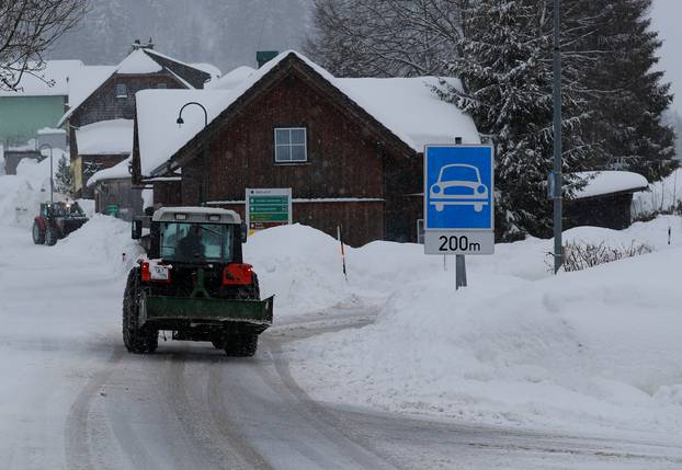 A tractor shovels snow on an icy road after heavy snowfall in Knoppen