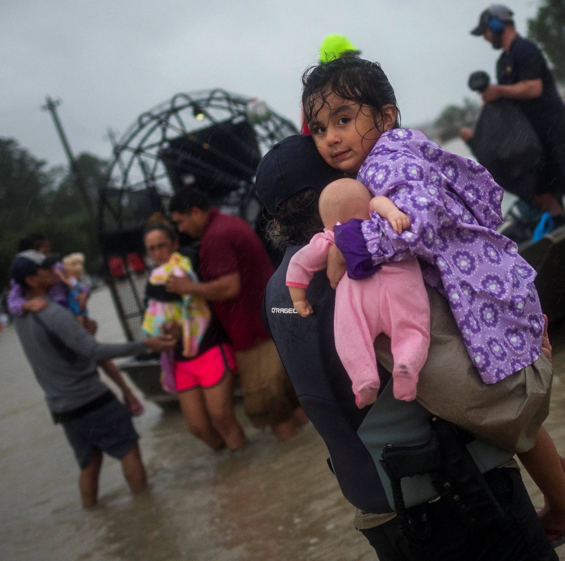 A woman holds a girl as her family arrives to high ground by boat due to floods caused by Tropical Storm Harvey along Tidwell Road in east Houston