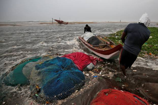 Fishermen move a fishing boat to a safer place along the shore before Cyclone Nivar
