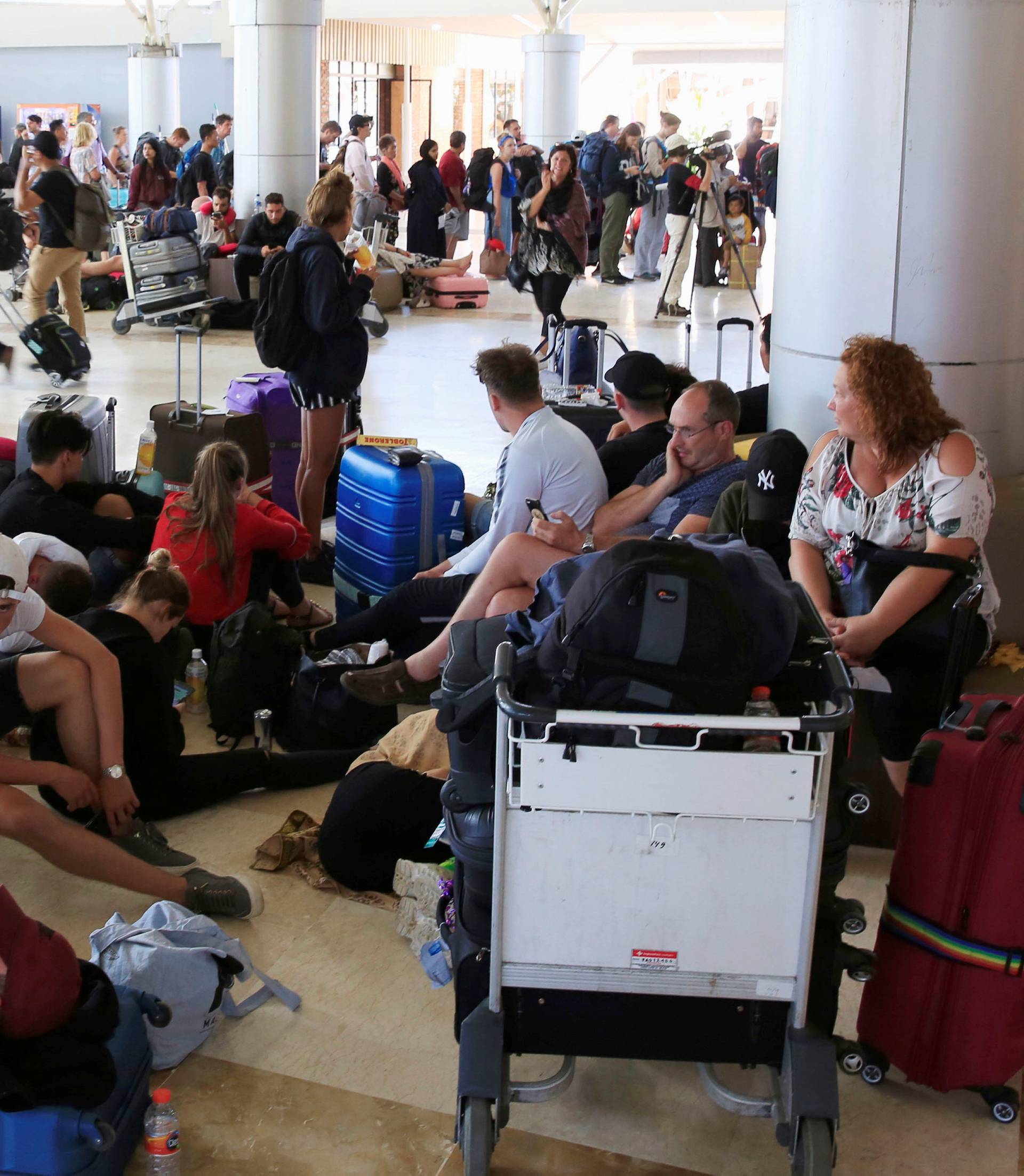 Foreign tourists sit and lie on the floor as they queue to leave Lombok Island after an earthquake hit, as seen at Lombok International Airport, Indonesia