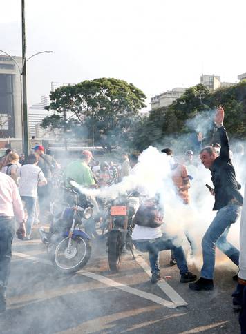 People react to tear gas near the Generalisimo Francisco de Miranda Airbase in Caracas