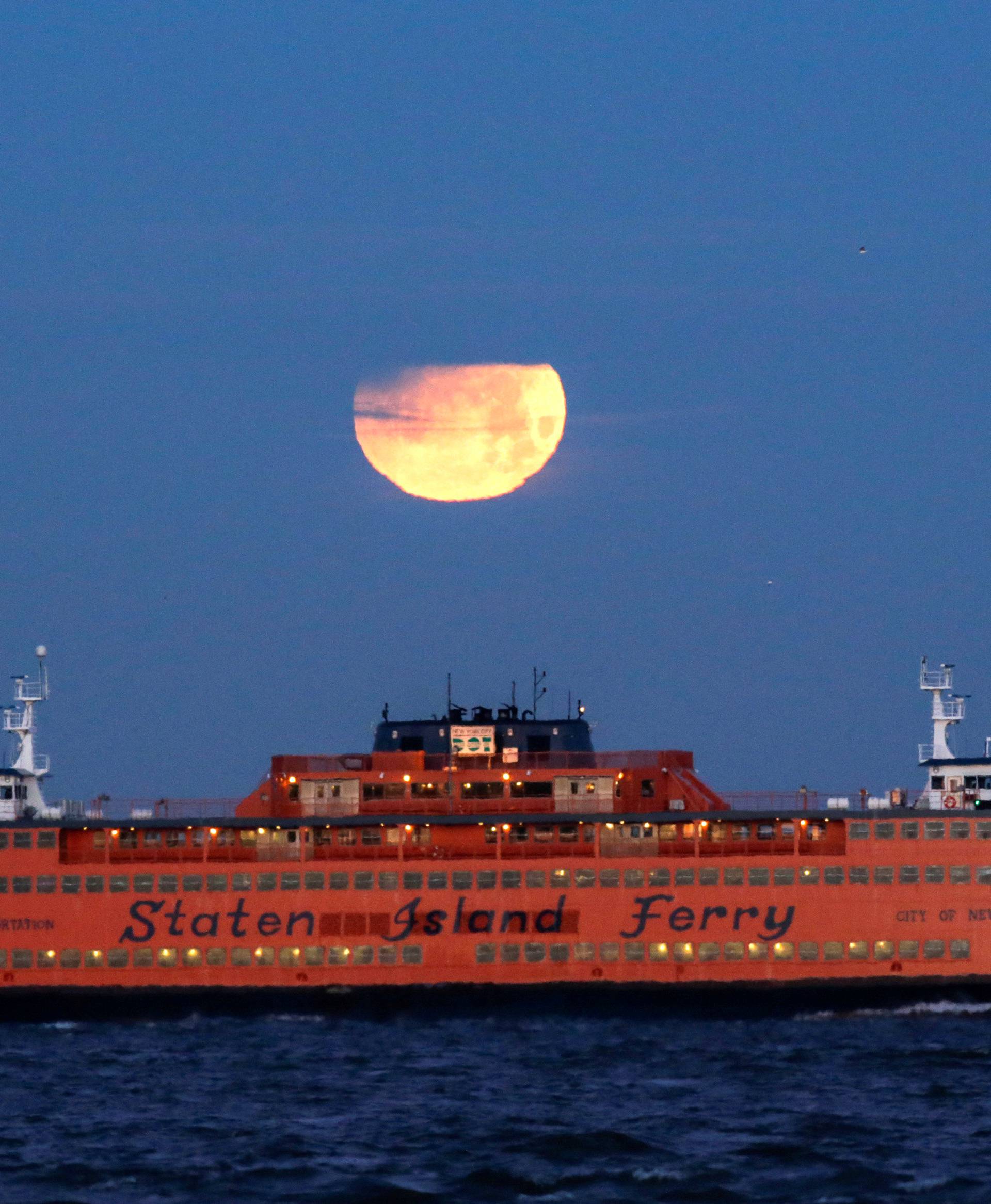 The "Super Blue Blood Moon" sets behind the Staten Island Ferry, seen from Brooklyn, New York