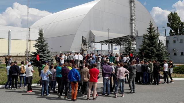 Visitors stand outside the New Safe Confinement (NSC) structure over the old sarcophagus covering the damaged fourth reactor at the Chernobyl Nuclear Power Plant, in Chernobyl