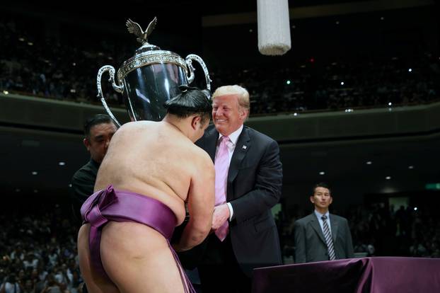 U.S. President Donald Trump presents the Presidentâs Cup to wrestler Asanoyama, the winner of the Summer Grand Sumo Tournament at Ryogoku Kokigikan Sumo Hall in Tokyo