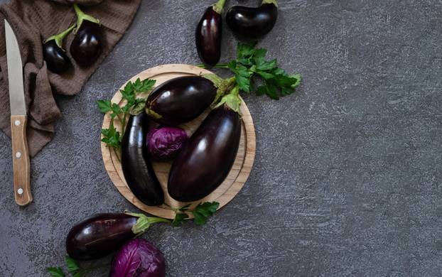 Fresh mini eggplant in a wooden plate on a white wooden background. Vegetables.