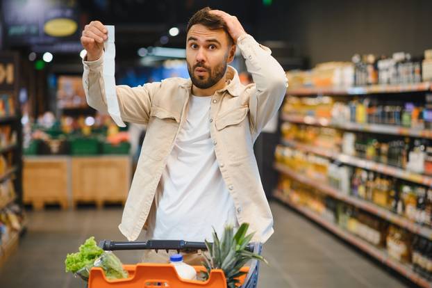 Man,Holding,A,Long,Supermarket,Receipt,,Expressing,Shock,And,Frustration
