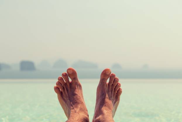closeup of male feet over sea and sky on beach