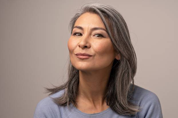 Charming Asian mature woman smiles at camera