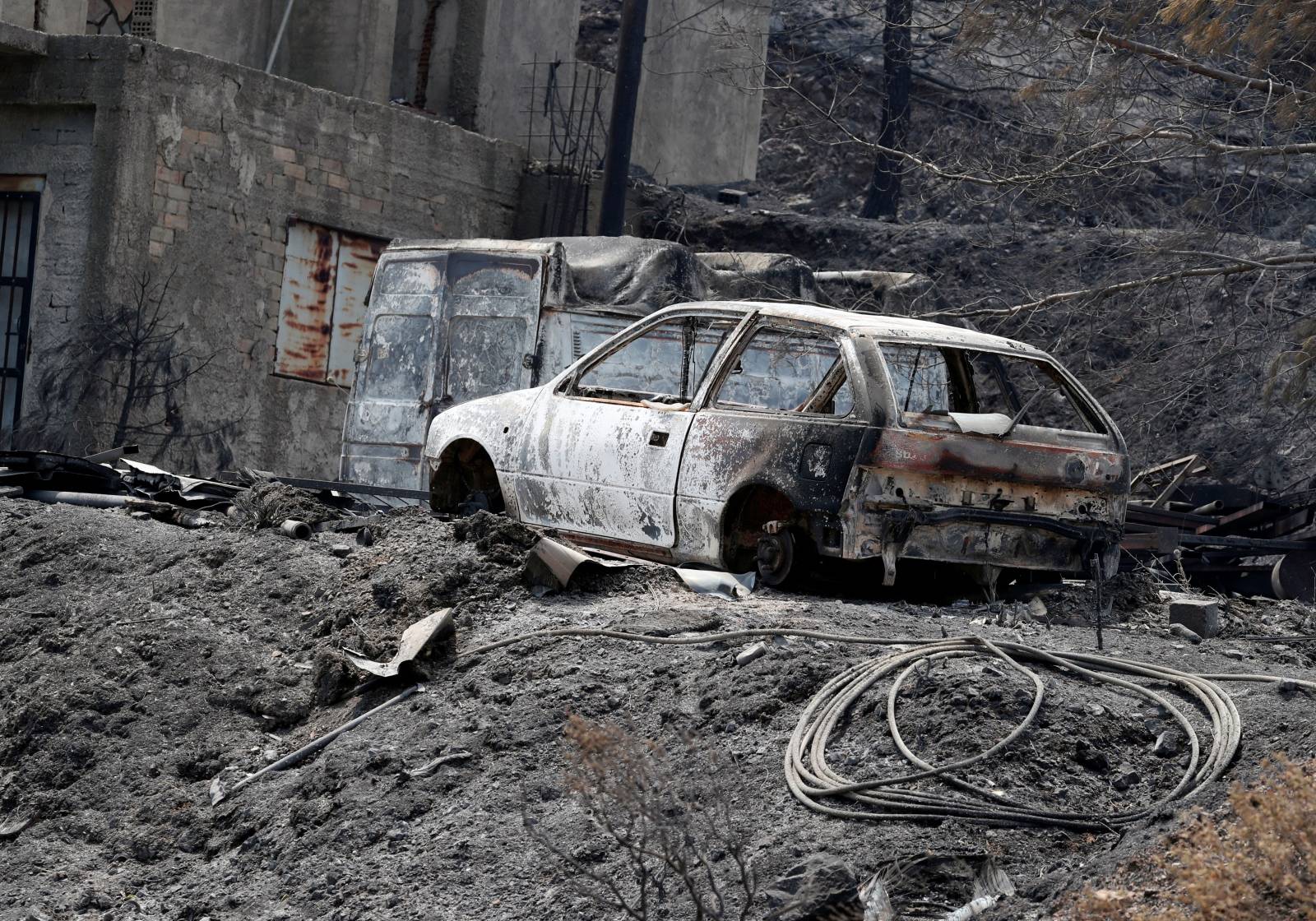Burned house and cars are seen following a wildfire near the village of Melini, in the Larnaca mountain region