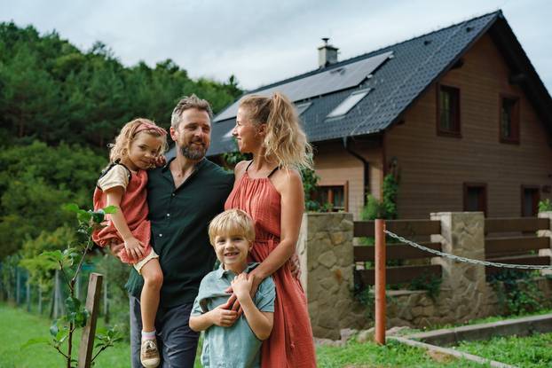 Happy,Family,Near,Their,House,With,Solar,Panels.,Alternative,Energy,