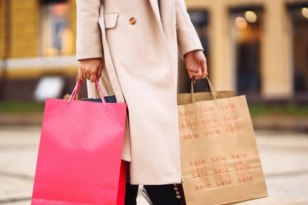 Shopping bags in the hands. Hand of young woman with multi-coloured bags with purchases.