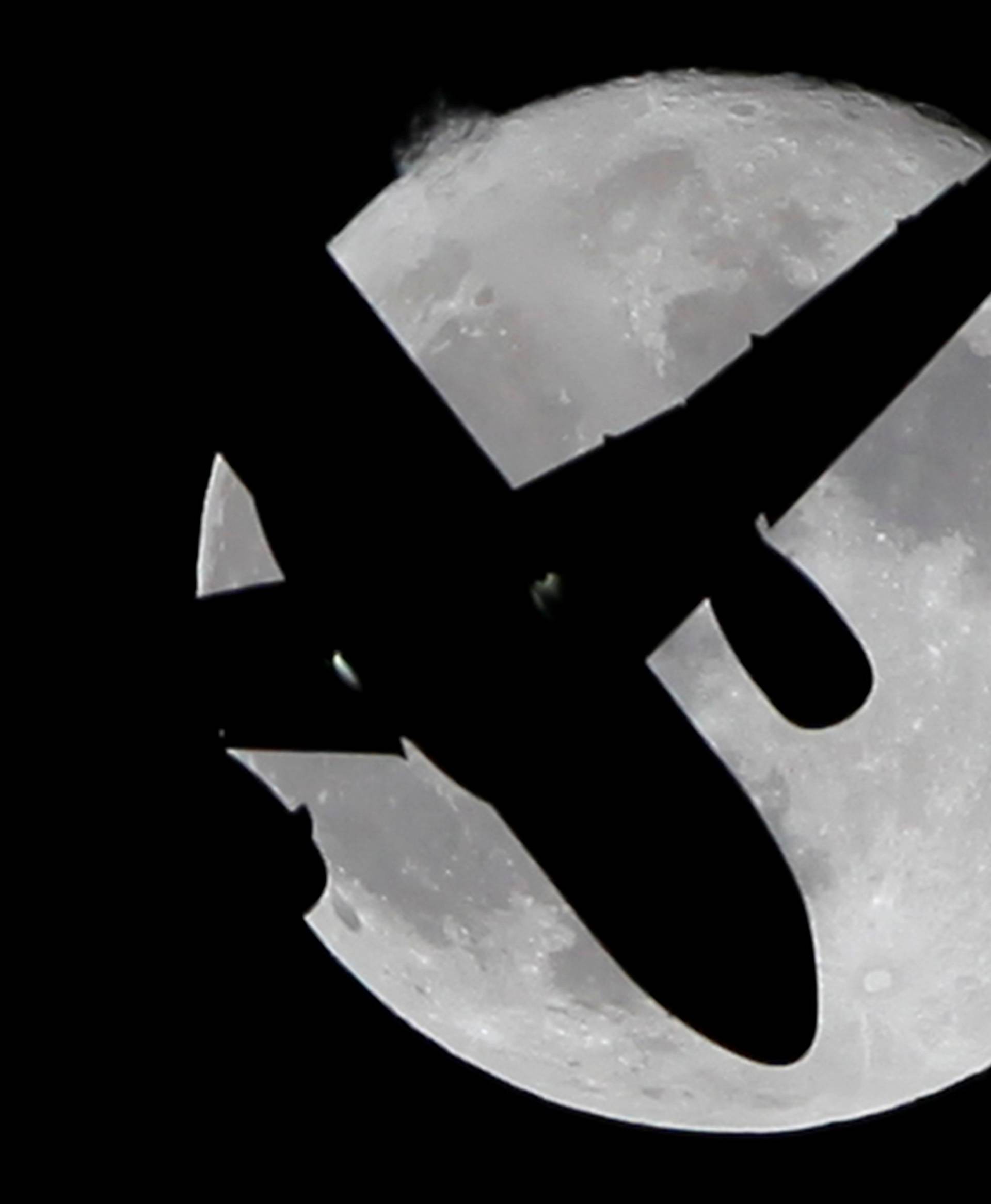 A Vueling passenger aircraft flies past a super moon in Ardales