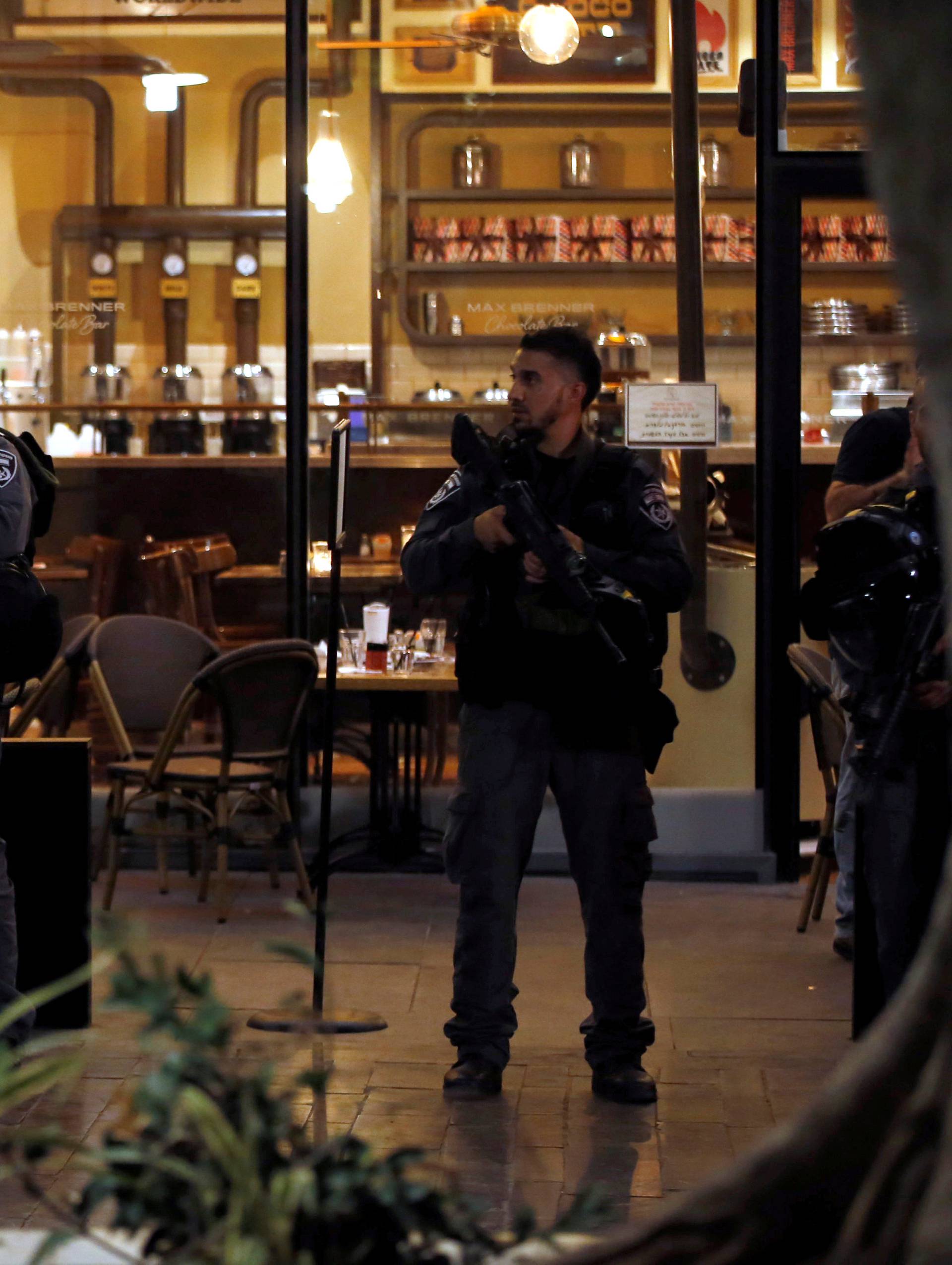 Israeli policemen secure the entrance to a restaurant following a shooting attack in the center of Tel Aviv