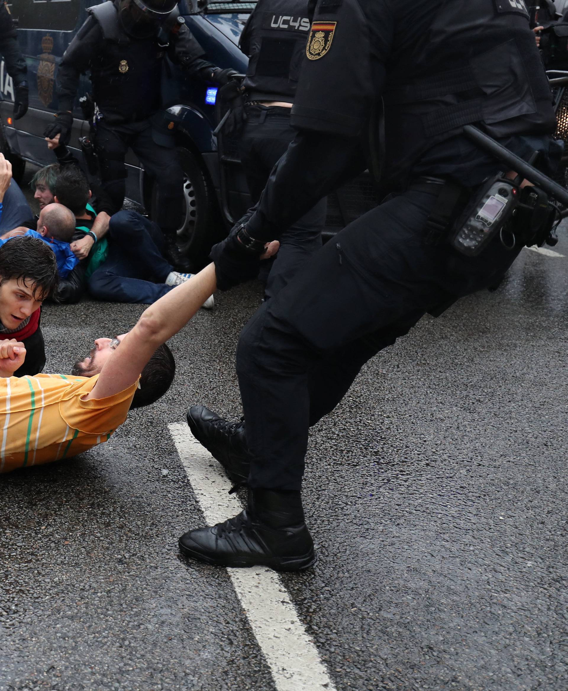 Riot police remove demonstrators outside a polling station for the banned independence referendum in Barcelona