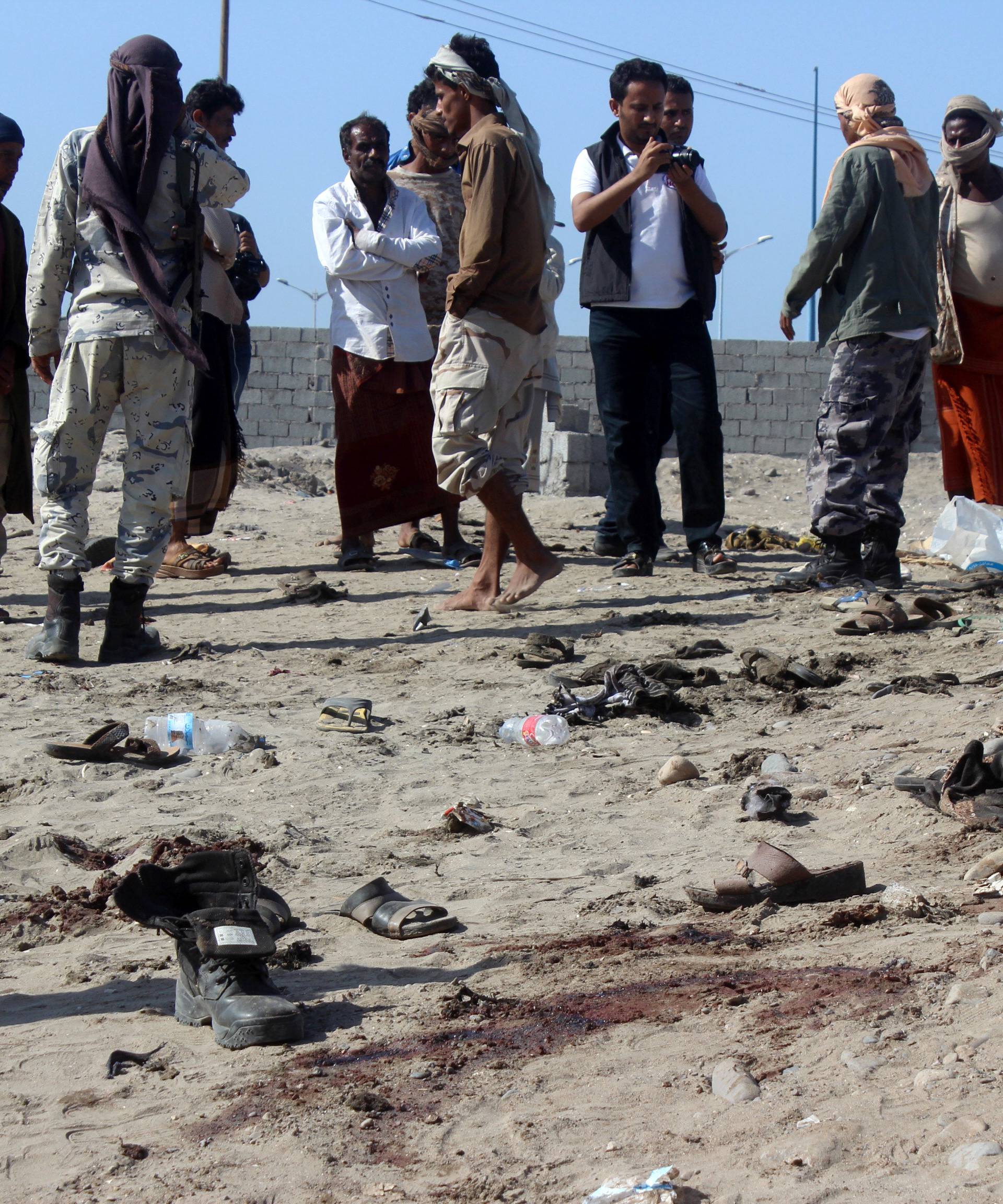 People gather at the site of a suicide bombing in the southern port city of Aden, Yemen