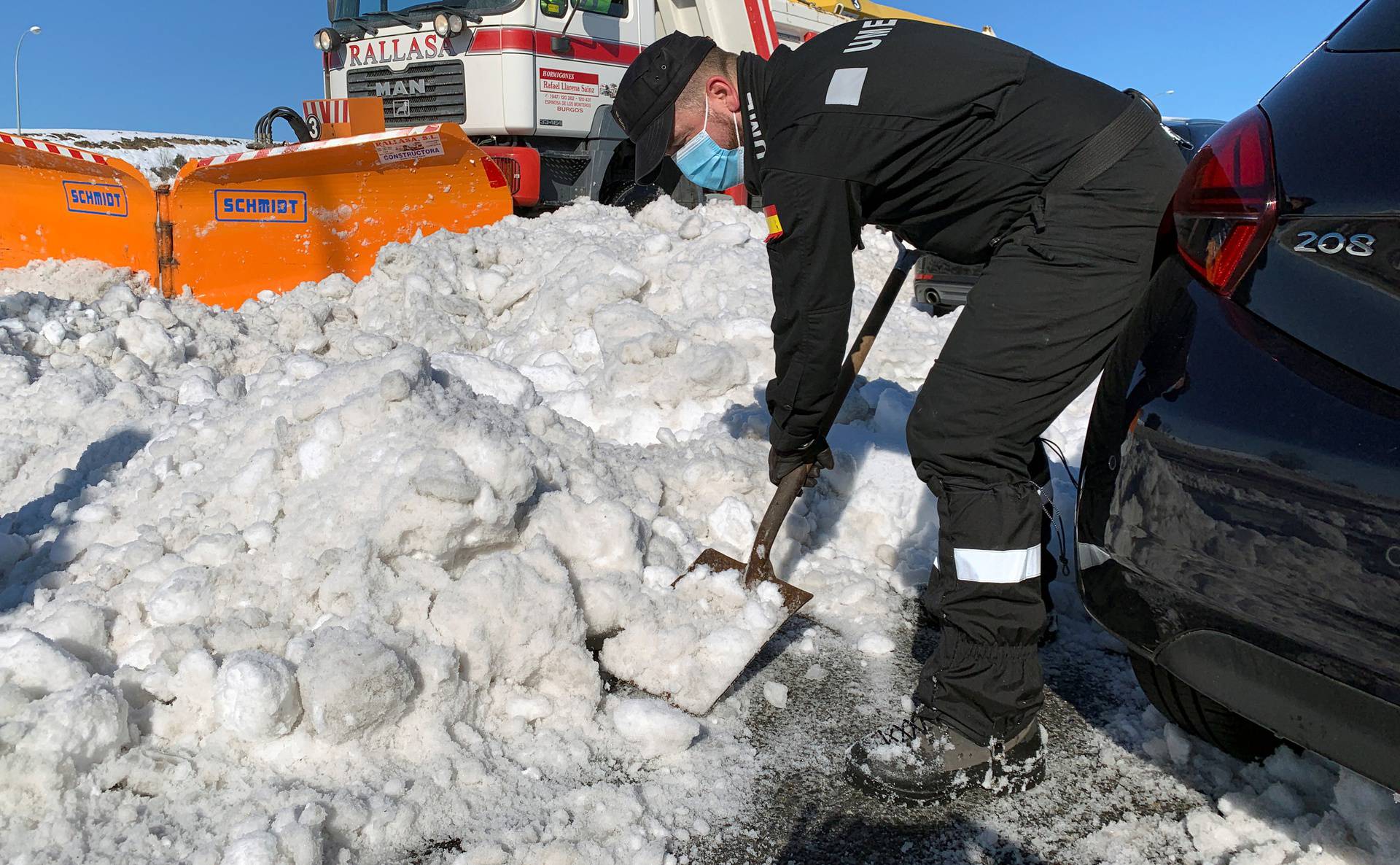 A member of Spain's military unit (UME) shovels snow next to cars accumulated on M-40 highway after heavy snowfall in Madrid