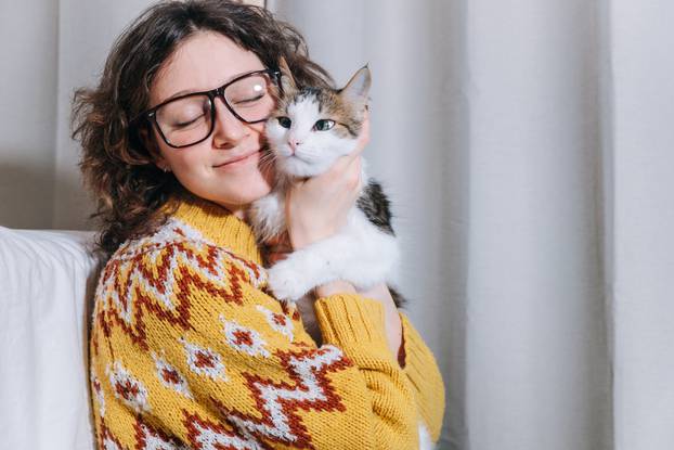 Cute freelancer girl working at home on a laptop and hugging her cat