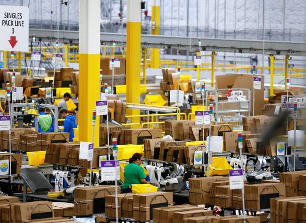 Employees work at pack stations at the Amazon fulfillment center in Kent