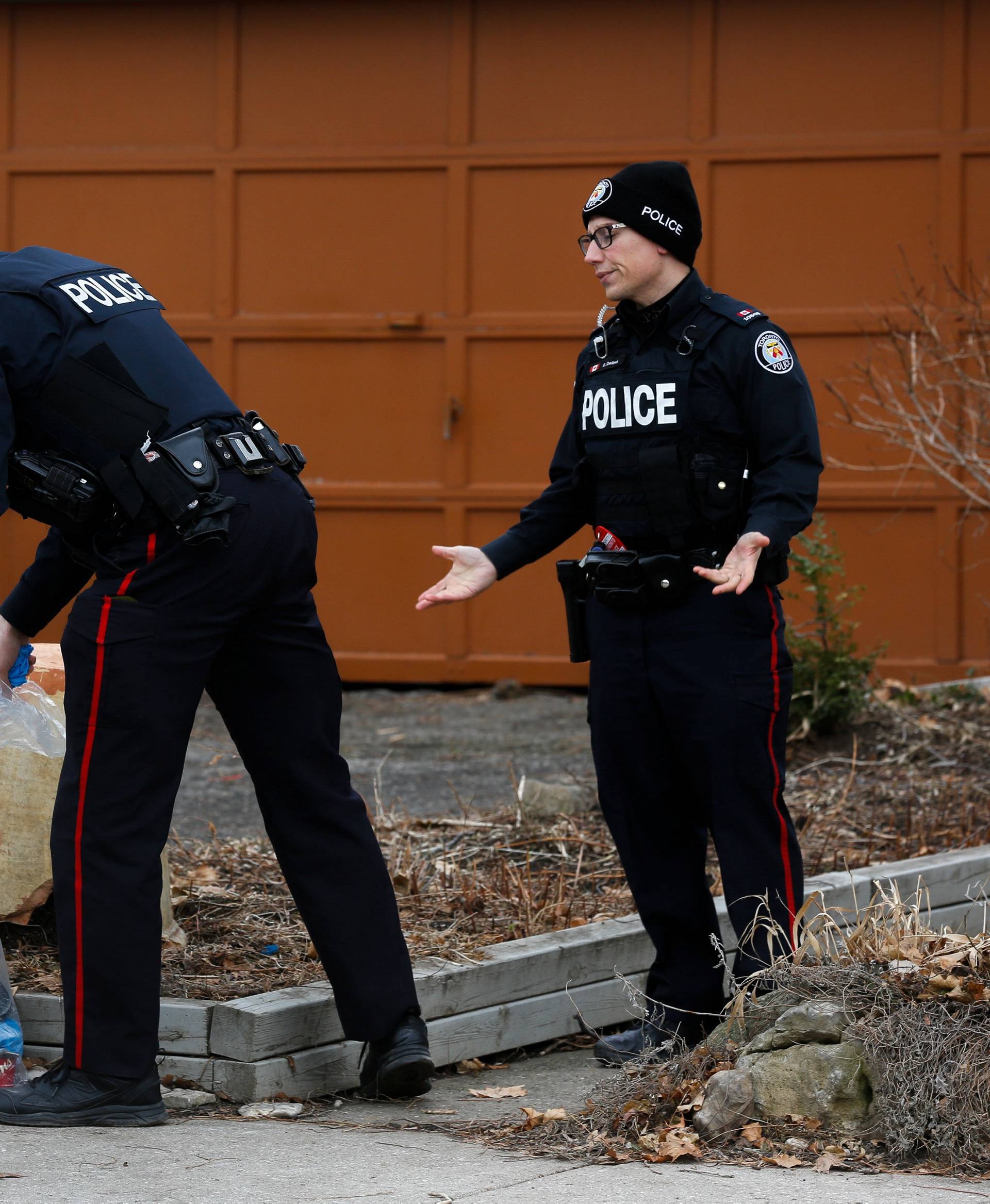 Police officers guard the grounds of a house they searched in Toronto