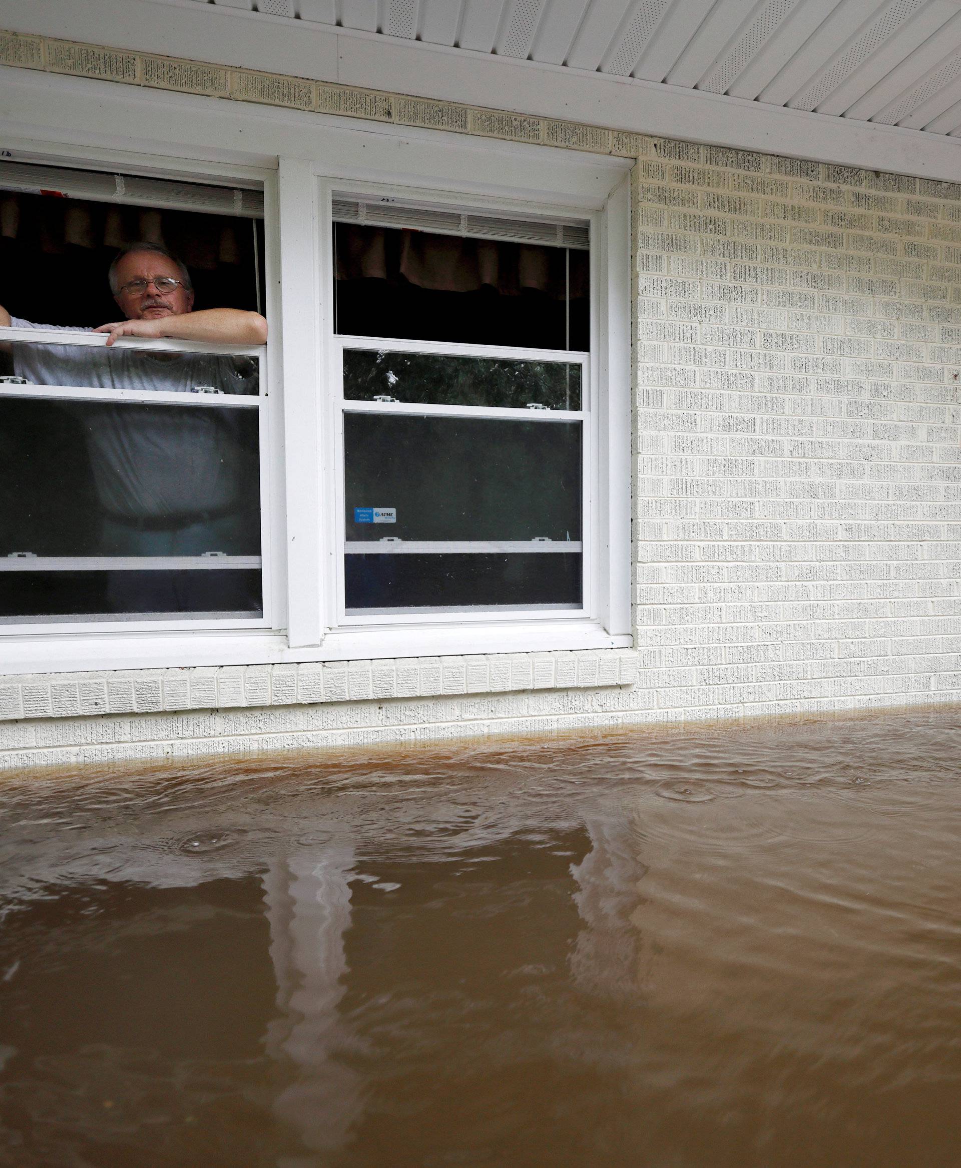 Gavrilovic peers out the window of his flooded home while considering whether to leave with his wife and pets as waters rise in North Carolina