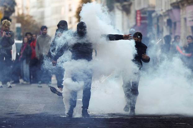 Demonstrators react amid tear gas, the day after a national day of demonstrations against the cost of living and rising fuel prices, in Paris