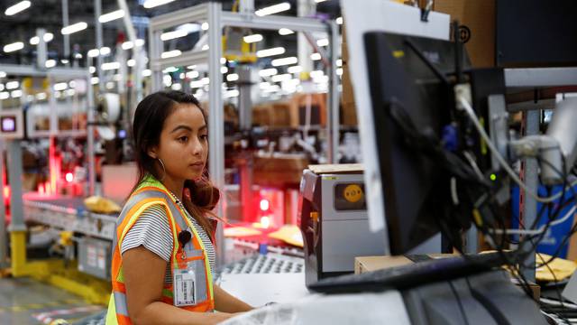 Employee Greenman works on processing packages kicked out by the automated scanning and labeling system at the Amazon fulfillment center in Kent