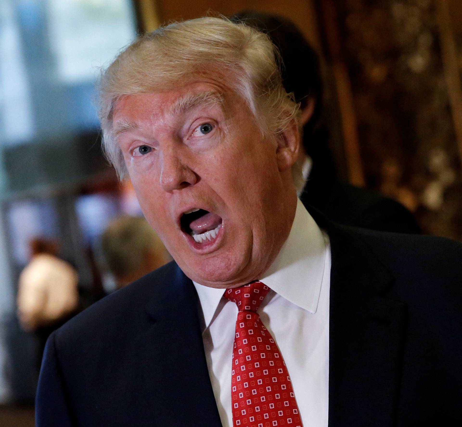 U.S. President-elect Donald Trump reacts to questions from reporters in the lobby at Trump Tower in New York