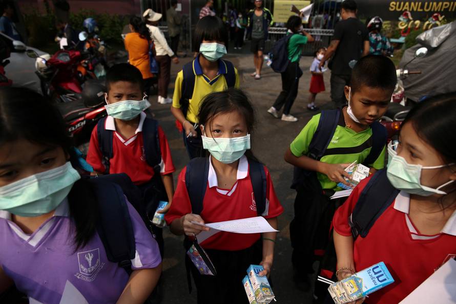 Students wear masks as they wait to be picked up during air pollution school closures in Bangkok