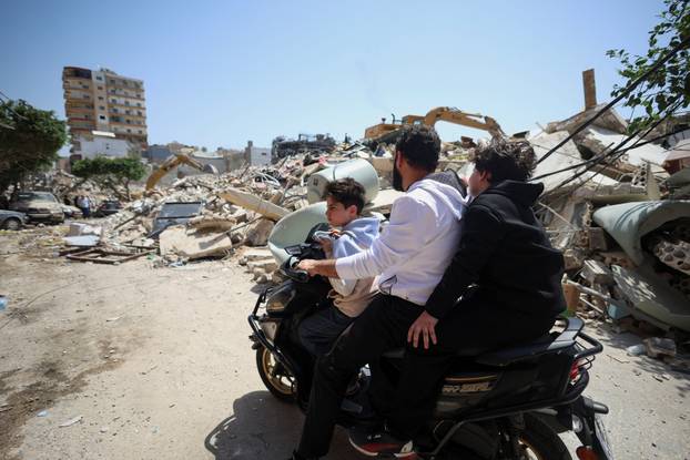 A man with children look at the site of an Israeli strike carried out before a 10-day ceasefire between Lebanon and Israel went into effect, in Tyre