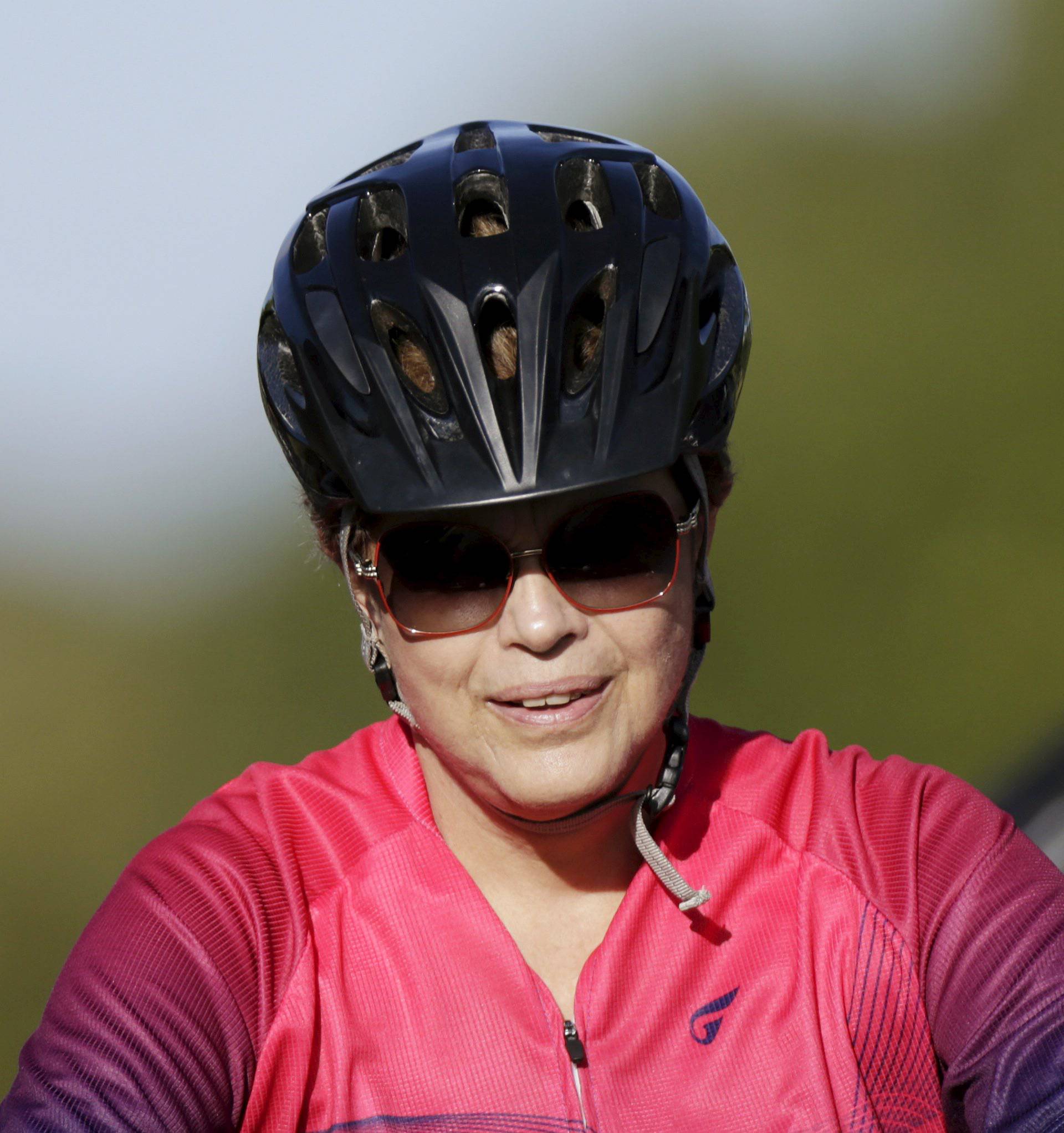 Brazil's President Dilma Rousseff rides her bicycle accompanied by bodyguards near the Alvorada Palace in Brasilia