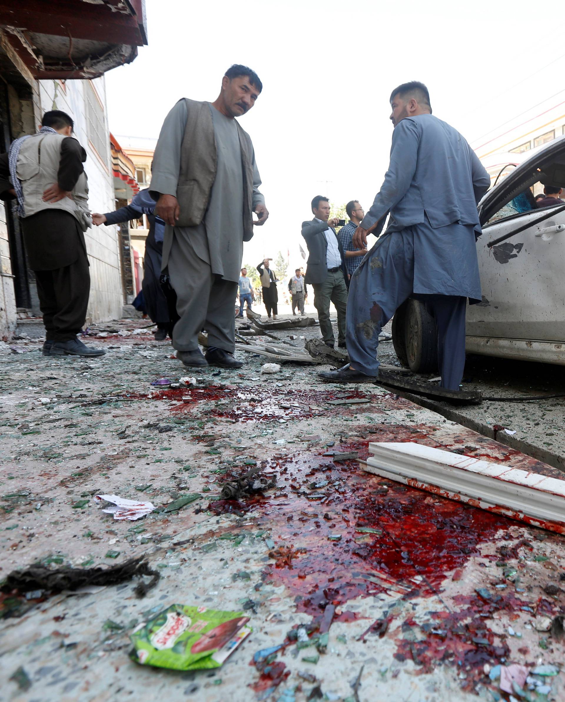 Afghan men inspect the site of a suicide bomb blast in Kabul