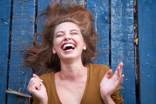 Beautiful caucasian young woman Lying on her back on wooden background. 