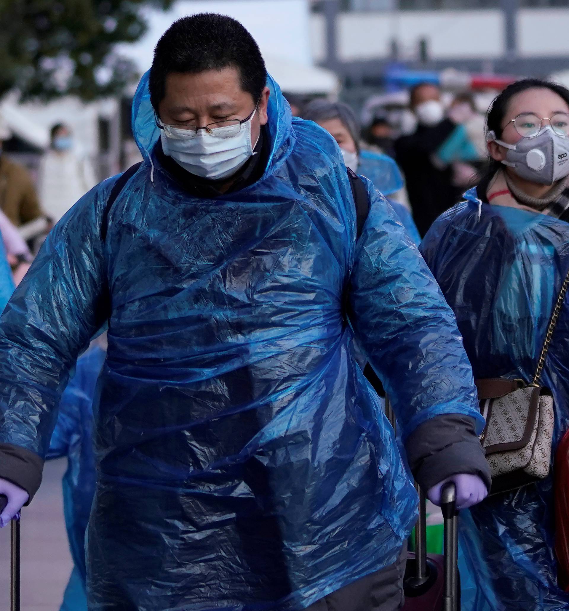 People wear face masks and plastic raincoats as a protection from coronavirus in Shanghai